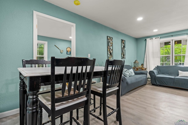 dining space featuring wood finished floors, recessed lighting, a textured wall, and baseboards
