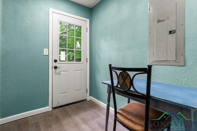 doorway featuring electric panel, wood finished floors, a textured wall, and baseboards
