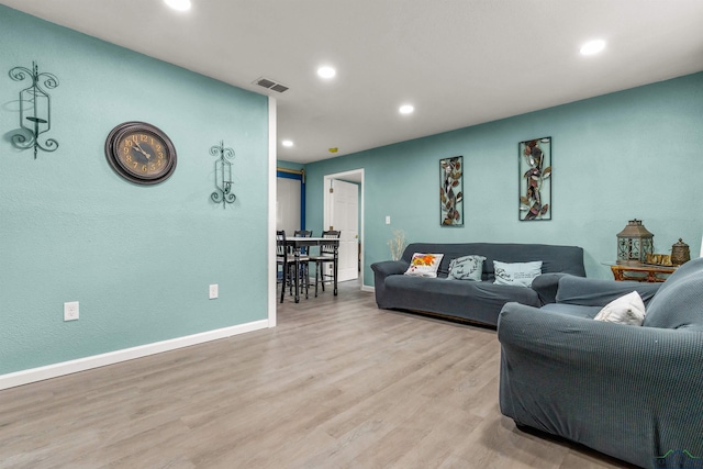 living room featuring visible vents, light wood finished floors, and recessed lighting