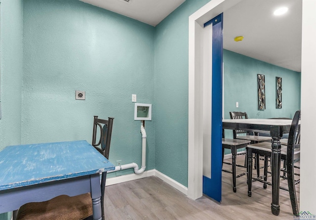washroom featuring wood finished floors, laundry area, electric dryer hookup, a textured wall, and baseboards
