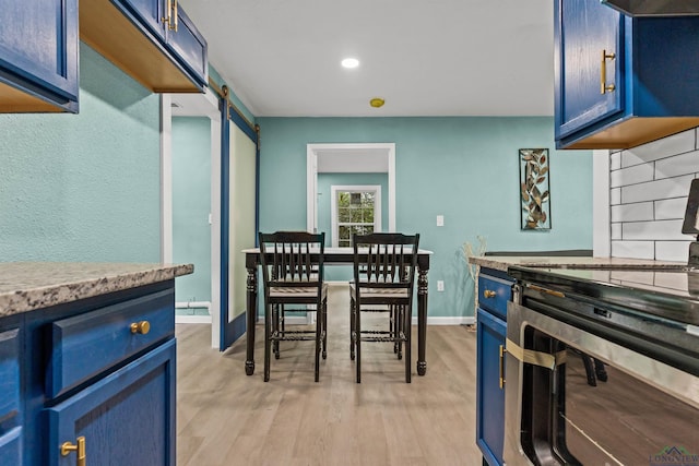 kitchen featuring range with electric cooktop, tasteful backsplash, light wood-style floors, baseboards, and blue cabinetry