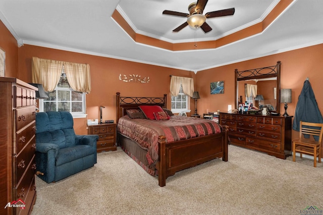 carpeted bedroom featuring multiple windows, ornamental molding, ceiling fan, and a tray ceiling