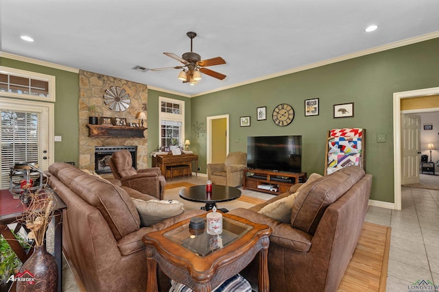 living room with ceiling fan, ornamental molding, a fireplace, and light tile patterned floors