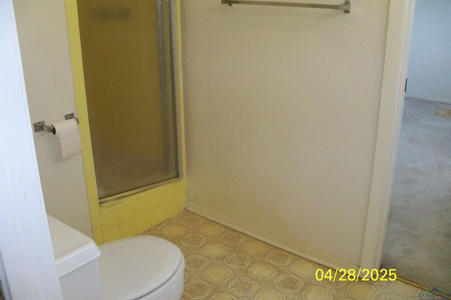 full bathroom with baseboards, a shower stall, and toilet