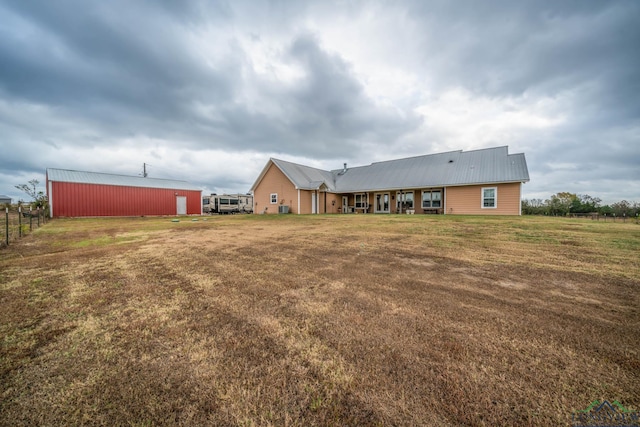 back of property featuring a lawn and an outbuilding