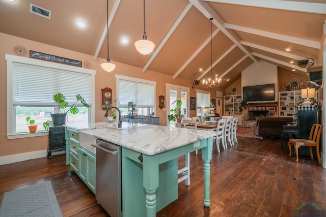 kitchen with a fireplace, pendant lighting, dishwasher, dark hardwood / wood-style floors, and an island with sink