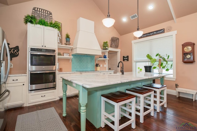 kitchen featuring light stone countertops, decorative light fixtures, decorative backsplash, custom exhaust hood, and appliances with stainless steel finishes