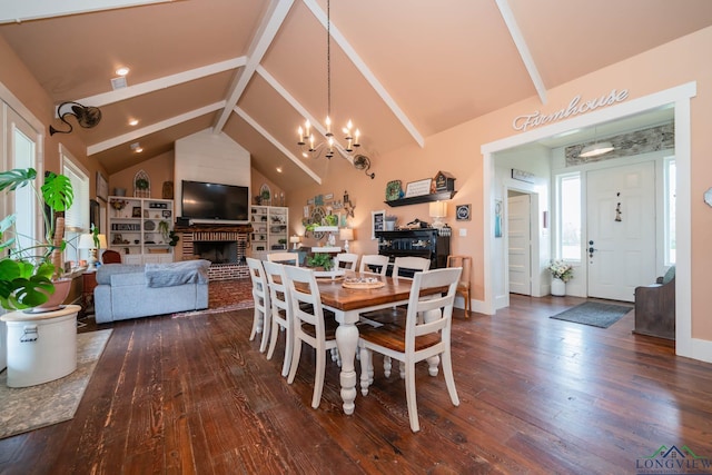 dining room with a fireplace, vaulted ceiling, dark wood-type flooring, and a notable chandelier