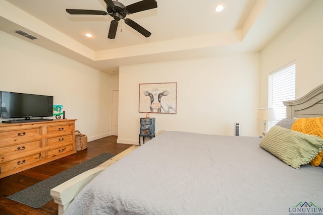 bedroom with a tray ceiling, ceiling fan, and dark hardwood / wood-style flooring