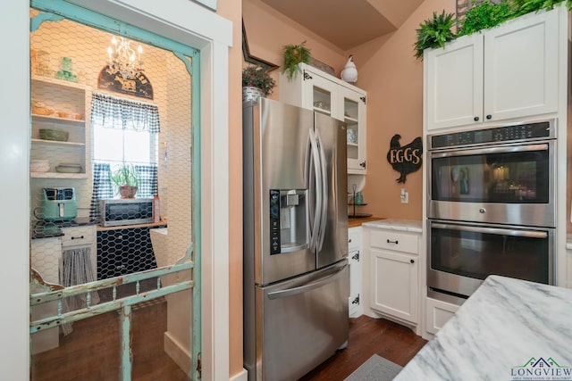 kitchen with light stone countertops, white cabinetry, dark wood-type flooring, and stainless steel appliances