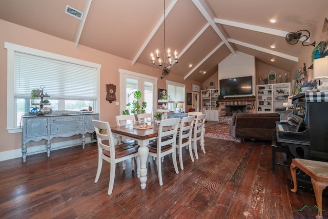 dining space featuring a fireplace, dark wood-type flooring, lofted ceiling, and a notable chandelier