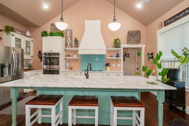 kitchen with appliances with stainless steel finishes, premium range hood, hanging light fixtures, and lofted ceiling