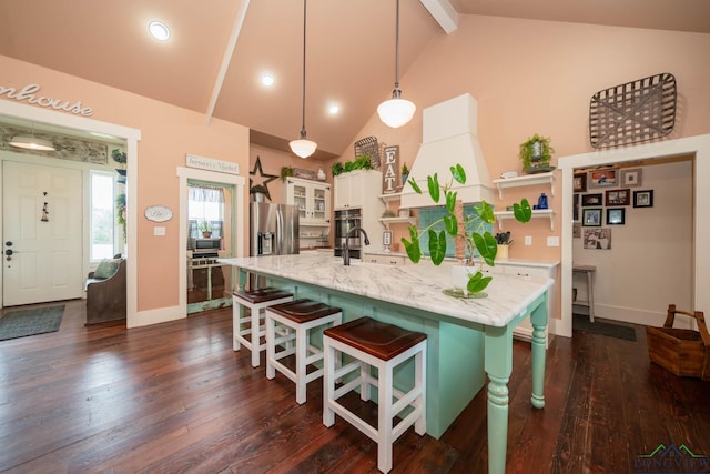 kitchen with a breakfast bar, stainless steel appliances, lofted ceiling with beams, decorative light fixtures, and white cabinets