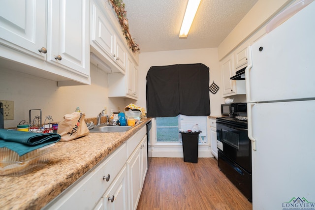 kitchen featuring light countertops, white cabinets, light wood finished floors, and black appliances