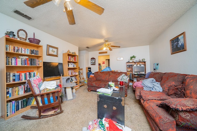 living room with carpet floors, a ceiling fan, visible vents, and a textured ceiling