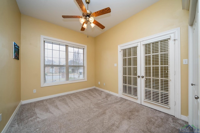 carpeted empty room featuring a ceiling fan, french doors, and baseboards