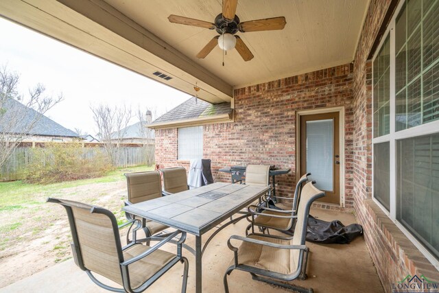 view of patio featuring outdoor dining area, fence, and a ceiling fan