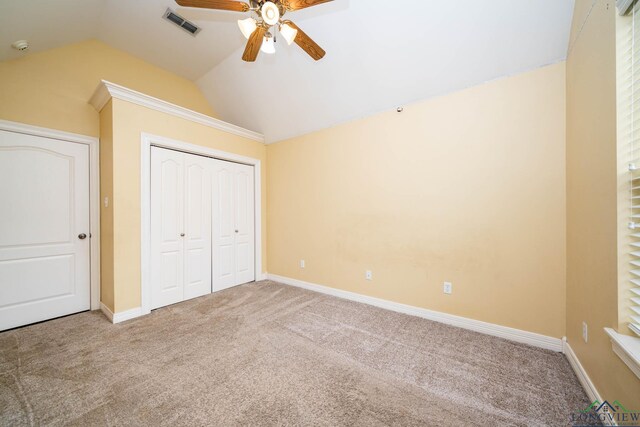 unfurnished bedroom featuring lofted ceiling, carpet floors, visible vents, baseboards, and a closet