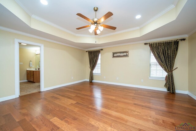 unfurnished room featuring crown molding, baseboards, a raised ceiling, and wood finished floors