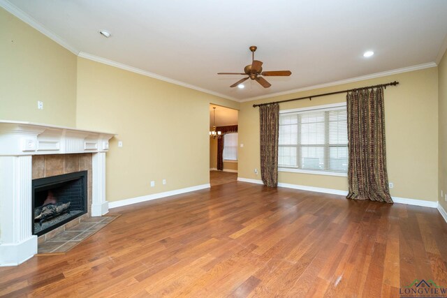 unfurnished living room featuring ornamental molding, a tiled fireplace, wood finished floors, and baseboards