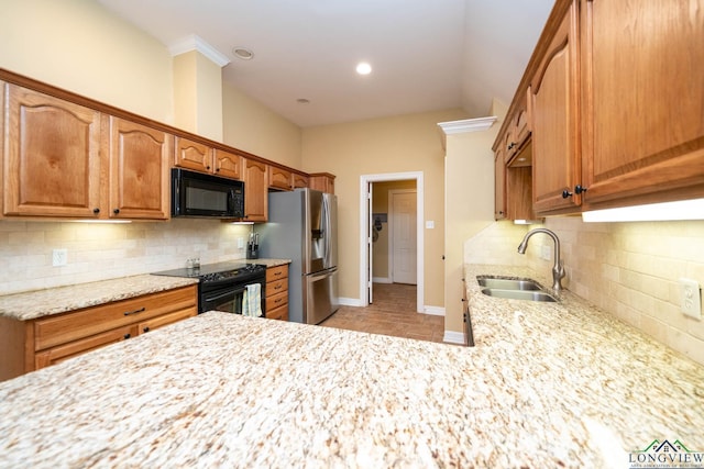 kitchen with black appliances, light stone counters, a sink, and baseboards