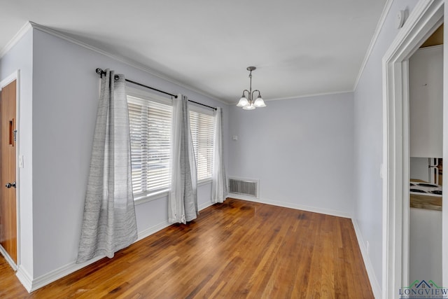 unfurnished dining area featuring hardwood / wood-style flooring, ornamental molding, and an inviting chandelier