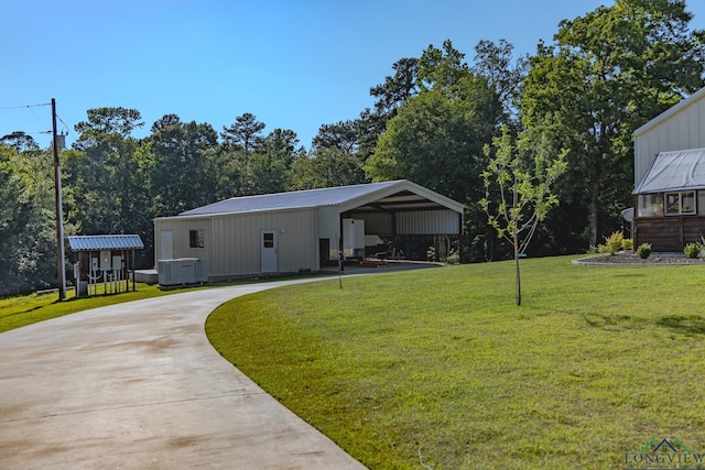 view of yard featuring central AC unit, a carport, and an outbuilding