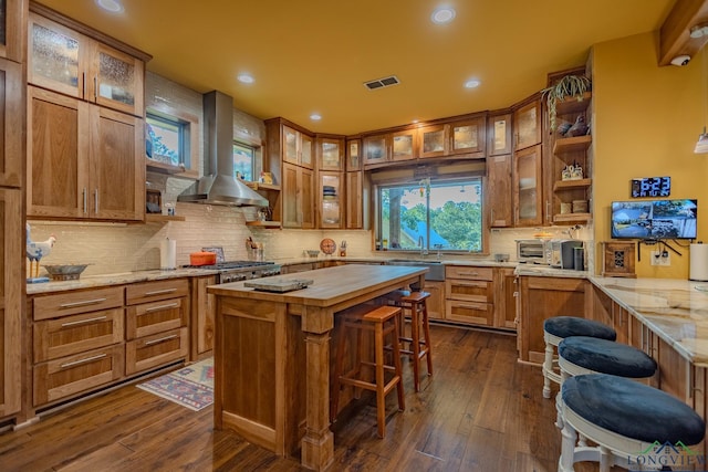 kitchen with dark hardwood / wood-style floors, a kitchen island, butcher block counters, and wall chimney range hood