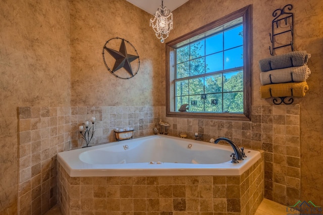 bathroom featuring tile patterned floors, tiled bath, and an inviting chandelier