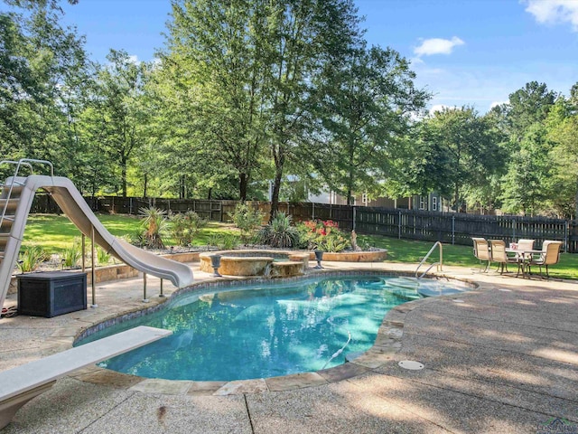 view of pool with a yard, a jacuzzi, a diving board, a water slide, and a patio