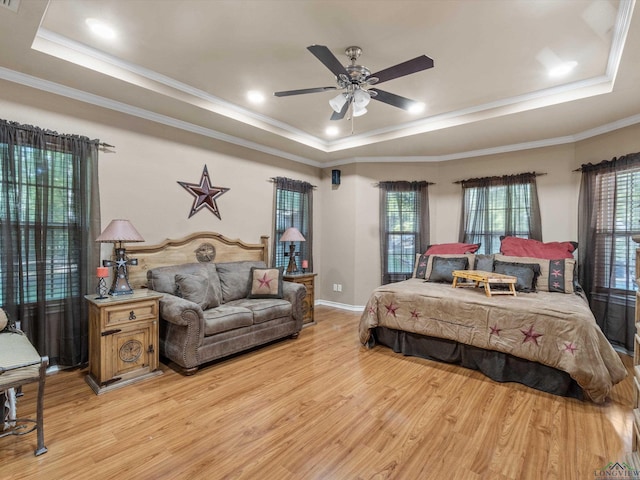 bedroom with ceiling fan, a raised ceiling, and light wood-type flooring