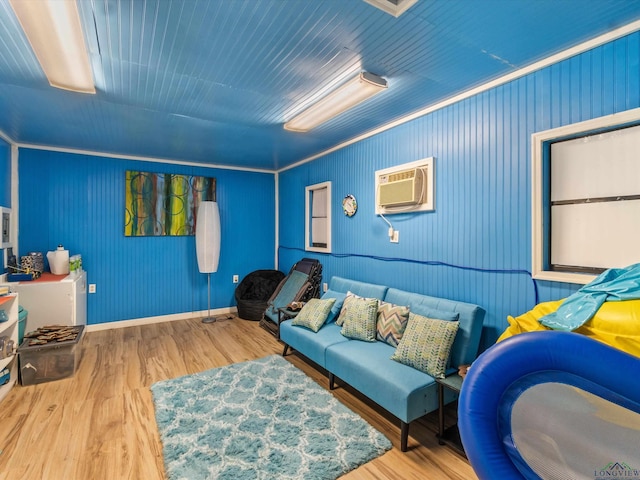 living room featuring wood-type flooring, ornamental molding, and a wall mounted AC