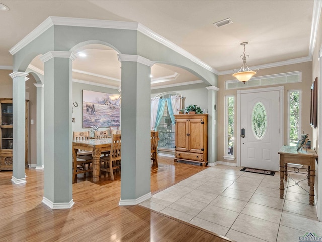 foyer featuring light tile patterned floors, ornate columns, and ornamental molding