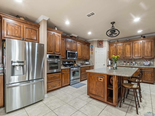 kitchen featuring a center island, decorative backsplash, light stone countertops, ornamental molding, and appliances with stainless steel finishes