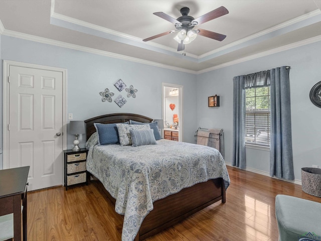 bedroom with wood-type flooring, a tray ceiling, ceiling fan, and ornamental molding