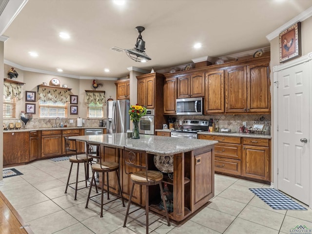 kitchen with decorative backsplash, ornamental molding, stainless steel appliances, light tile patterned floors, and a kitchen island