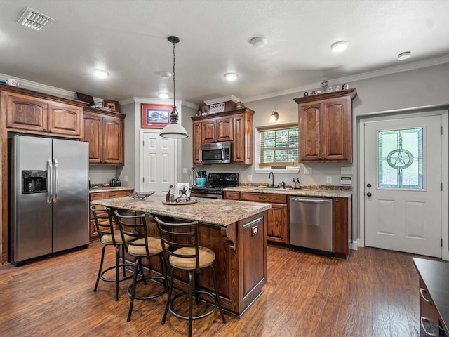 kitchen with ornamental molding, stainless steel appliances, dark wood-type flooring, decorative light fixtures, and a kitchen island