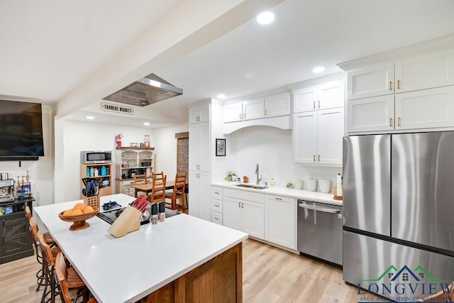 kitchen featuring white cabinetry, sink, a center island, light hardwood / wood-style floors, and stainless steel appliances