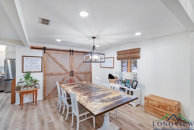 dining area featuring a barn door and light hardwood / wood-style floors