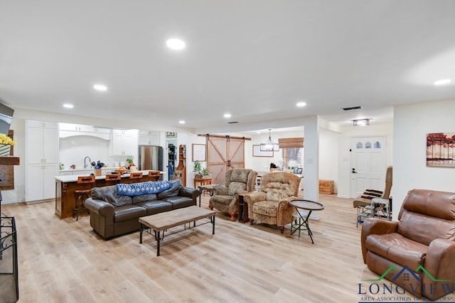 living room featuring a barn door and light wood-type flooring