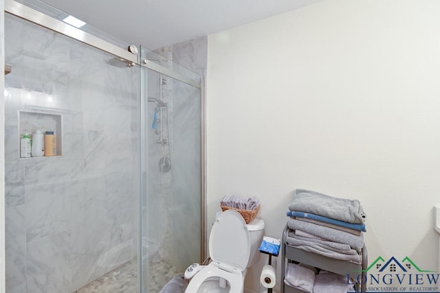 bathroom featuring a shower with door and toilet