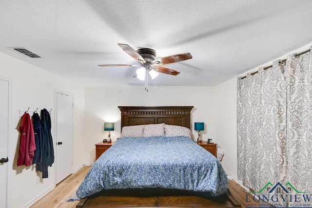 bedroom with ceiling fan, a textured ceiling, and light hardwood / wood-style flooring