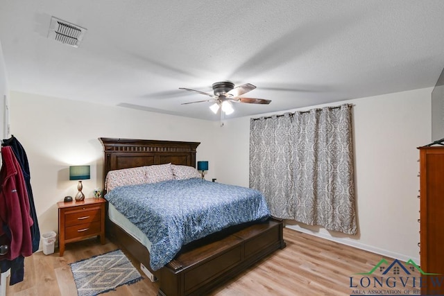 bedroom featuring ceiling fan, light hardwood / wood-style floors, and a textured ceiling