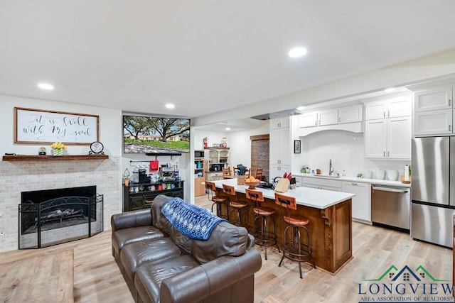 kitchen featuring a kitchen island, a breakfast bar area, white cabinets, light hardwood / wood-style floors, and stainless steel appliances