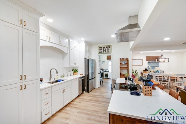 kitchen with sink, hanging light fixtures, light wood-type flooring, appliances with stainless steel finishes, and white cabinets