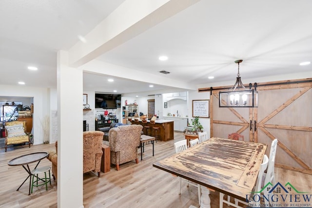 dining space with light hardwood / wood-style flooring and a barn door