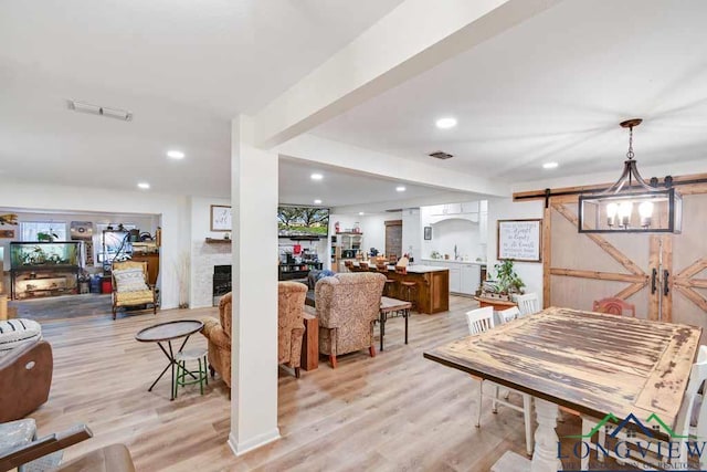 dining space with a barn door, sink, and light wood-type flooring