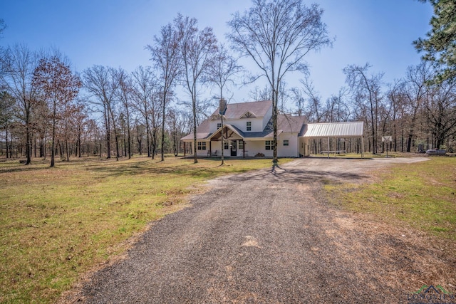 view of front of home with dirt driveway, a chimney, and a front lawn