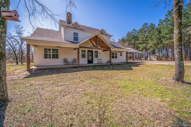 rear view of property featuring a patio, a lawn, and a chimney