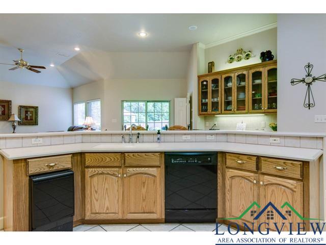1018 Brown Dr, Texarkana, TX 75501 - kitchen featuring black dishwasher, a sink, open floor plan, a ceiling fan, and glass insert cabinets